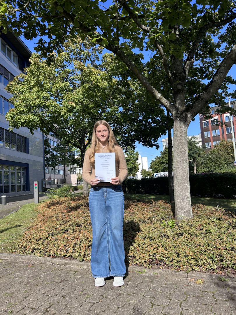 Praktikumsbericht Schülerin hält eine Urkunde über den 2. Platz für den besten Praktikumsbericht hoch.
